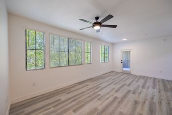 an empty living room with a ceiling fan and windows
